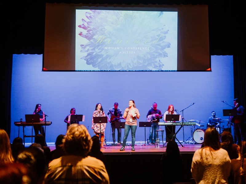 speaker on stage at conference with worship band